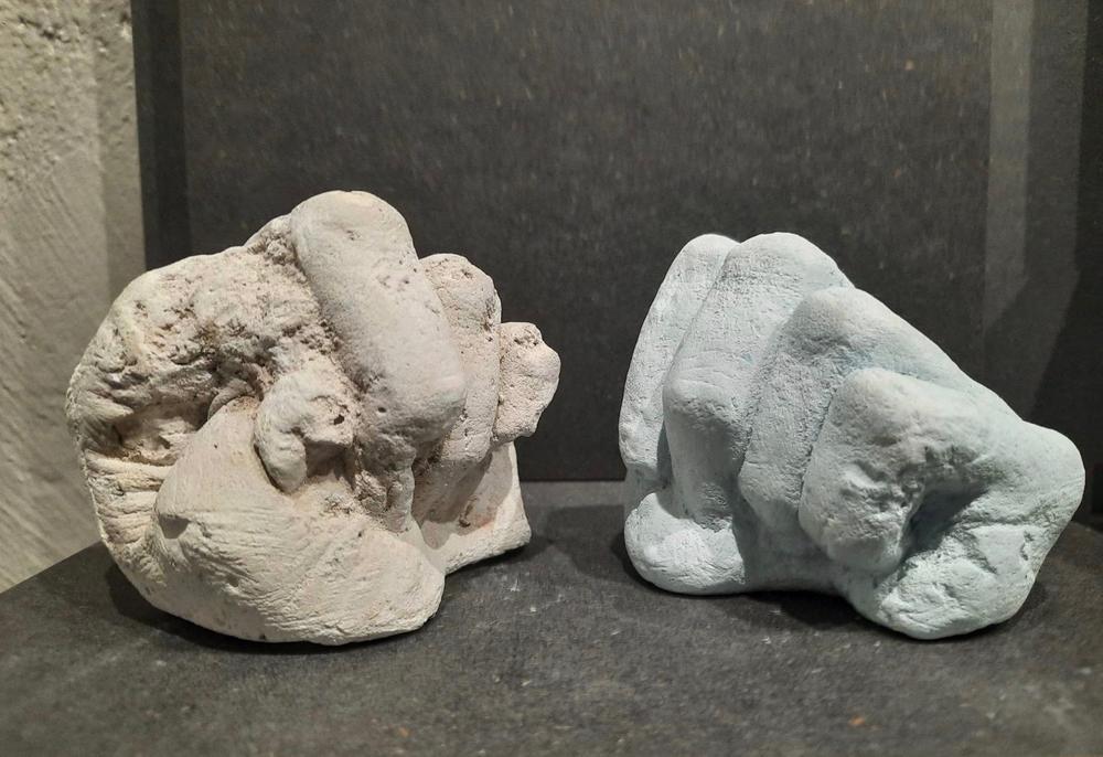 Two fist plaster sculptures in light brown and light blue.